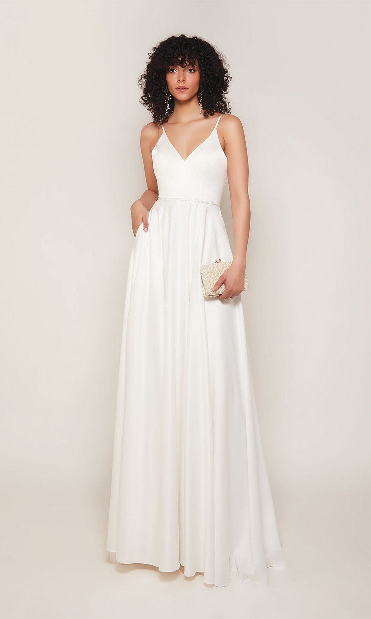 A woman stands against a plain background, holding a small beige clutch. She wears the Alyce 7089 Long Formal Dress—a sleeveless, white, floor-length gown that exudes minimalist elegance and simplicity.